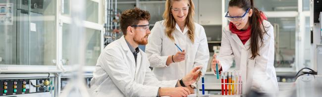 Drei Studierende beim Experimentieren im Labor