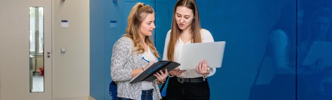 Zwei Studentinnen unterhalten sich auf dem Weg zur Vorlesung