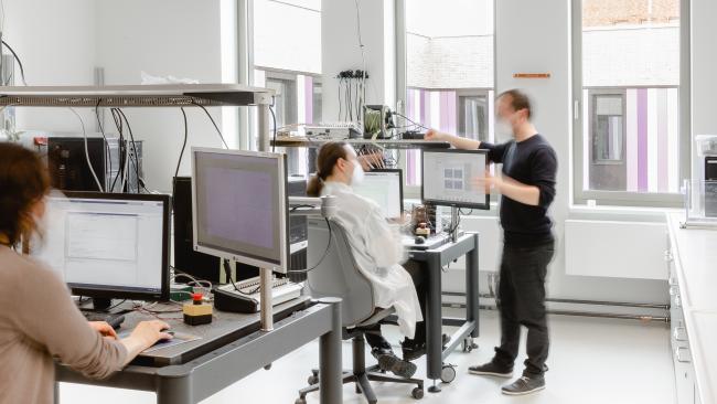 Ein Labor mit drei Wissenschaftlern. Das Bild ist leicht unscharf.