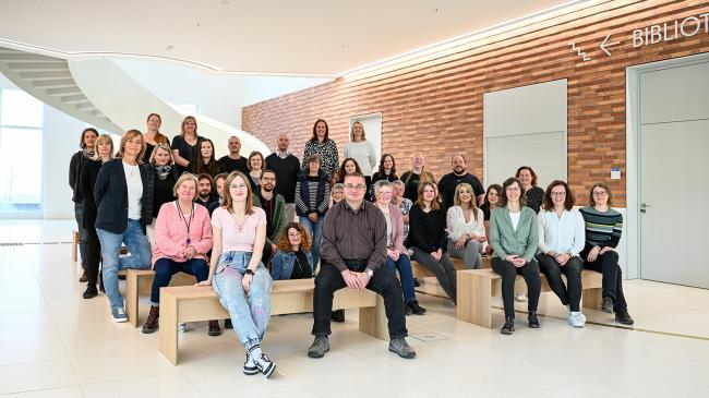 Viele Personen stehen und sitzen vor einer Treppe